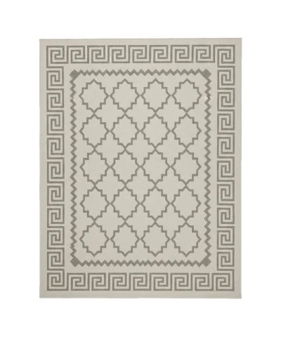 Rectangular grey polyester rug with a geometric pattern and Greek key border on a wooden outdoor deck with patio furniture.